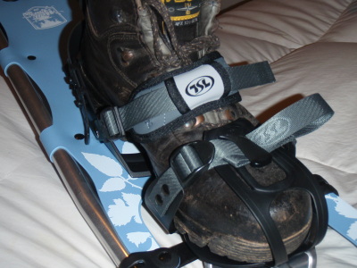 The snowshoes with a boot inside the straps from the front.